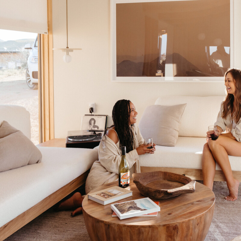 Two women drinking wine in living room.